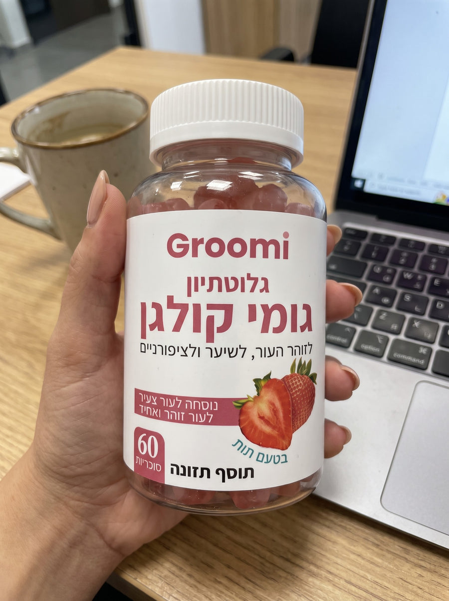 יד מחזיקה בקבוק גומי קולגן של Groomi ליד המחשב