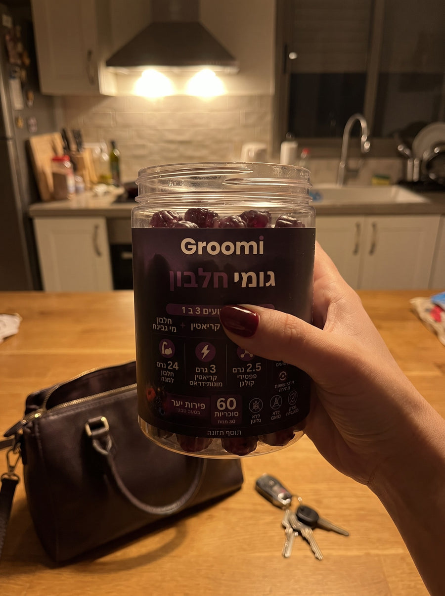 יד מחזיקה צנצנת גומי חלבון של Groomi במטבח בערב
